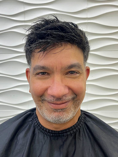 Angel Santiesteban sonriendo con el sistema capilar: pelo oscuro y corto, texturizado hacia adelante.